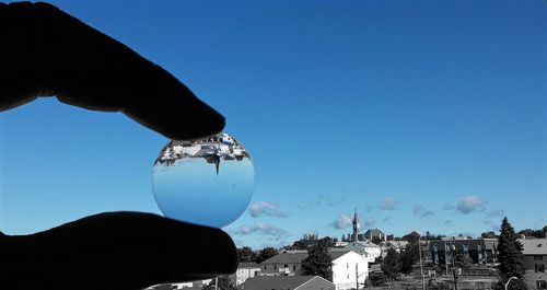 Close-up of hand against blue sky