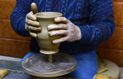 Craftsperson shaping pot on pottery wheel