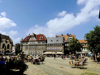 People on street amidst buildings in city against sky