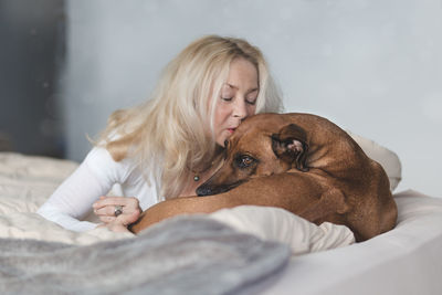 Young woman with dog on bed at home