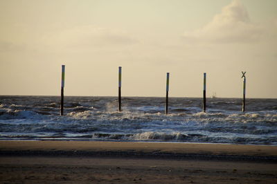 Wooden posts on beach against sky