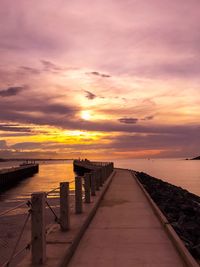 Narrow jetty leading to calm sea at sunset