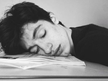 Close-up of young man leaning on book at table