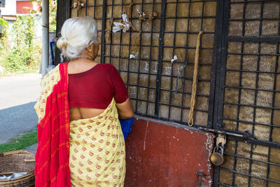 Rear view of woman standing by metal structure