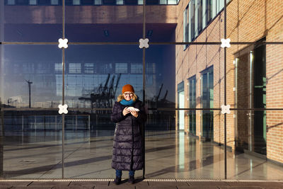 Senior woman standing in front of modern office building on sunny day