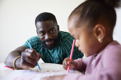 Father and daughter drawing together at home