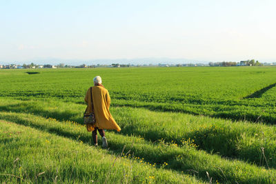 Rear view full length of woman walking on agricultural field against sky