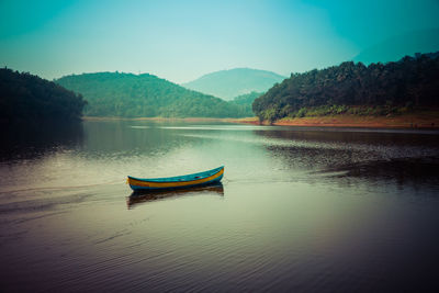 Boat moored on lake against sky