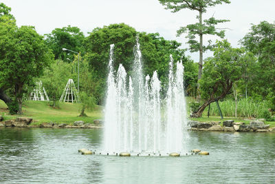 Fountain in lake against trees