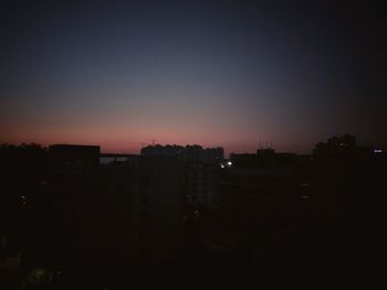 Silhouette cityscape against sky at night