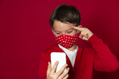 Midsection of man holding mobile phone against red background