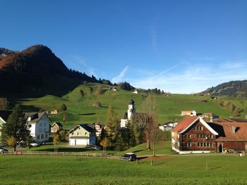 Houses on green landscape against clear sky