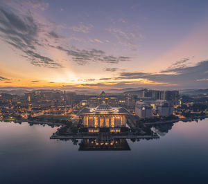 Illuminated buildings in city against sky during sunset