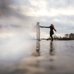 Man and woman standing in water against sky
