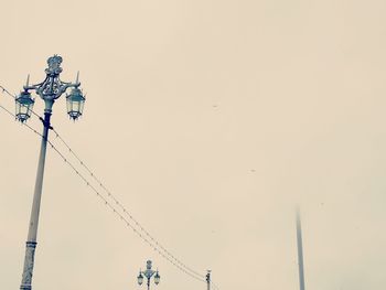 Low angle view of birds on cable against clear sky