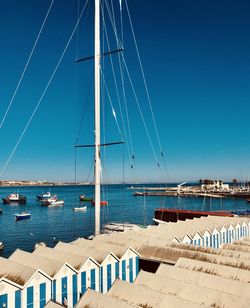 Sailboats moored in sea against blue sky