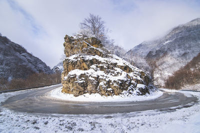 View of road amidst snow covered mountains against sky during winter