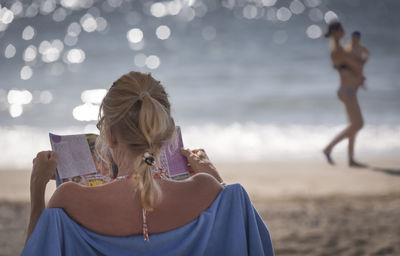 Rear view of women sitting on beach