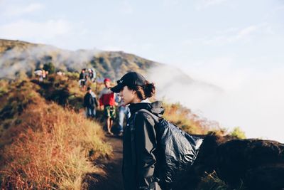 Side view of man standing on mountain against sky