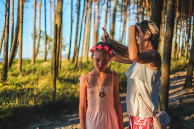 Woman adjusting hair of daughter at forest