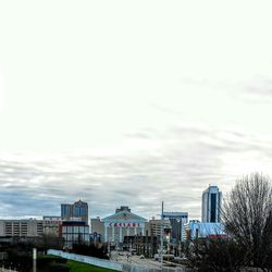 Buildings in city against cloudy sky