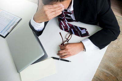 Midsection of man using mobile phone while sitting on table