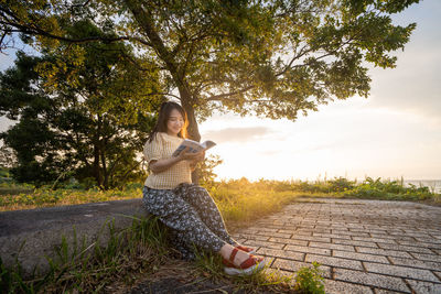 Portrait of woman sitting on tree trunk