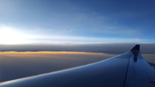 Cropped image of airplane flying against sky during sunset