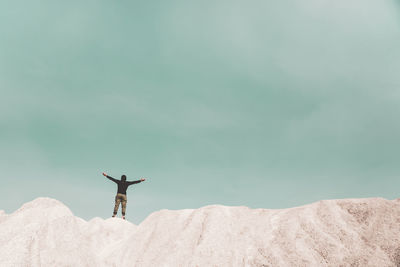 Man with arms outstretched against sky