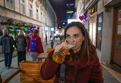 Woman drinking beer while sitting at outdoor cafe 