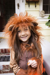 Portrait of smiling girl in halloween costume standing against house