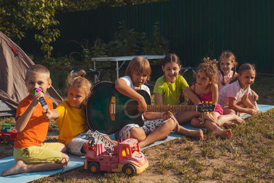 Group of friends playing guitar at park