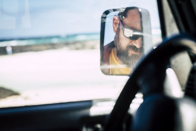 Reflection of man seen in side-view mirror of car