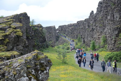 People walking on rocks against mountains