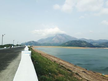 Road by lake against mountains 