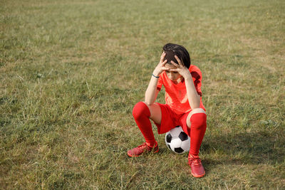 Side view of boy playing soccer on field