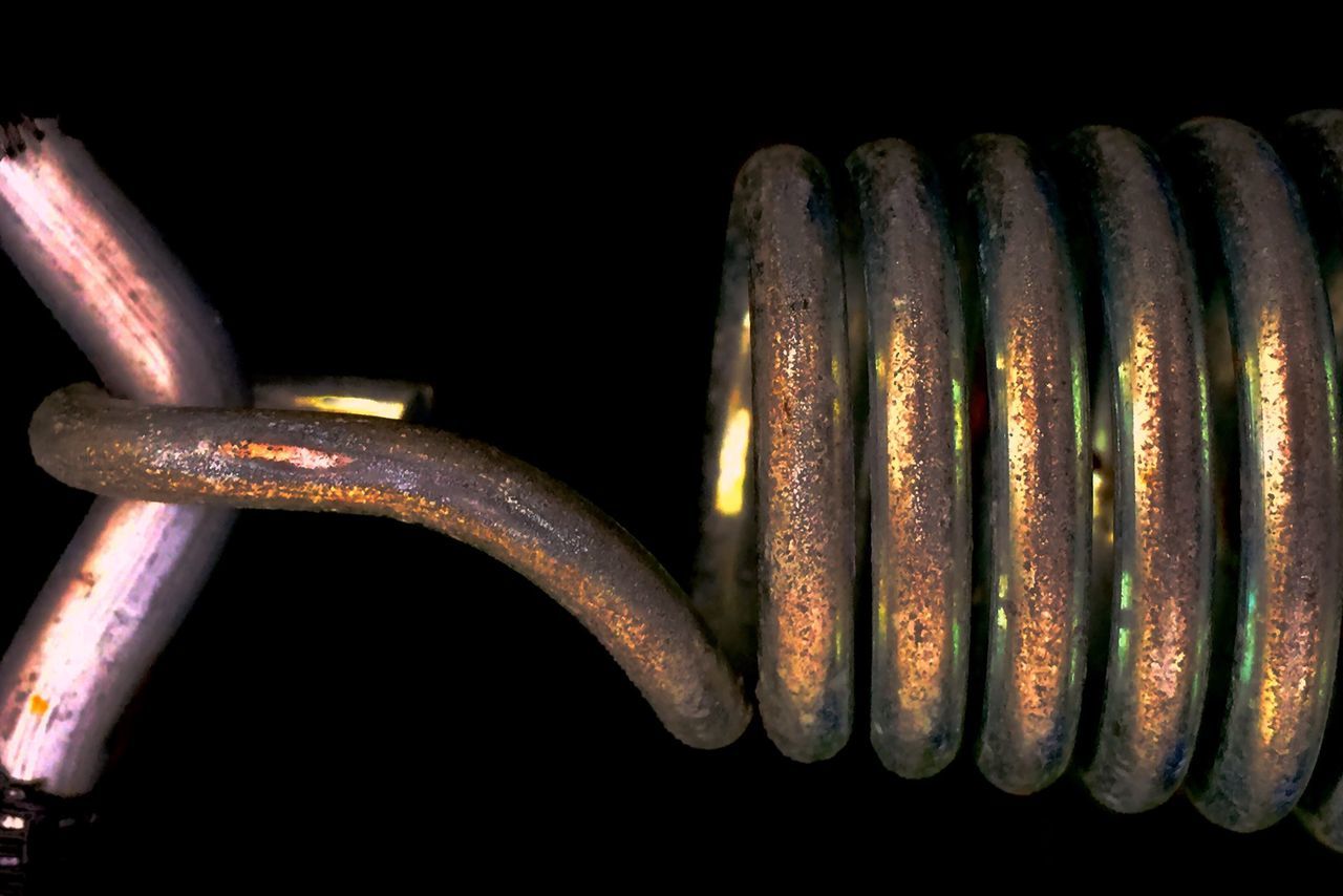 indoors, close-up, metal, still life, old, in a row, black background, studio shot, no people, metallic, side by side, repetition, detail, stack, large group of objects, night, shiny, history, rusty, factory