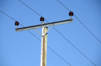 Low angle view of power lines against clear blue sky