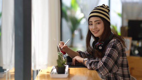 Portrait of smiling young woman holding table