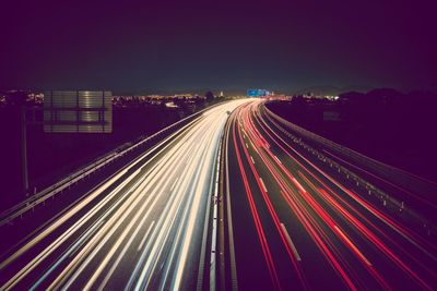 Light trails on road against sky at night