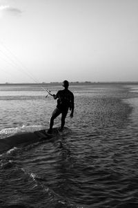Rear view of silhouette man standing in sea against sky