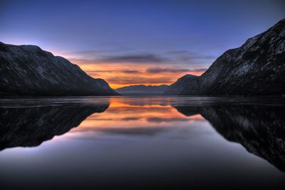 Scenic view of lake and mountains against dramatic sky