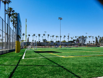 Scenic view of soccer field against clear blue sky