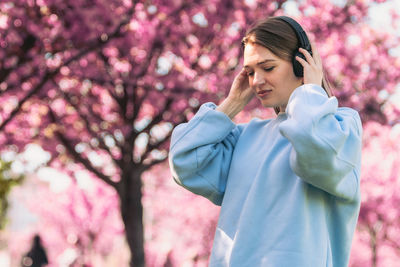 Side view of young woman standing against trees