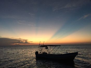 Silhouette boat in sea against sky during sunset