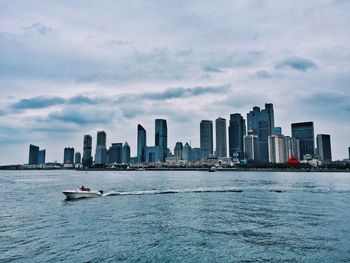 City at waterfront against cloudy sky