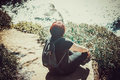 Rear view of woman sitting on rock at beach