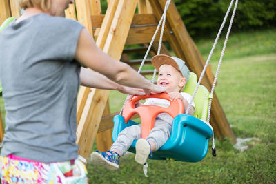 Rear view of boy sitting on swing at playground