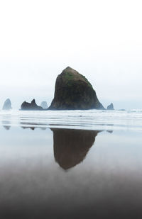 Reflection of rock formation in sea against sky