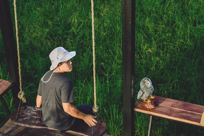 Woman sitting on wood against trees